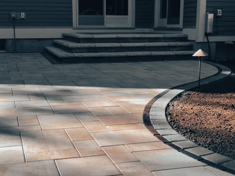A cozy backyard patio in Clifton Park, NY, featuring a fire pit and seating wall.