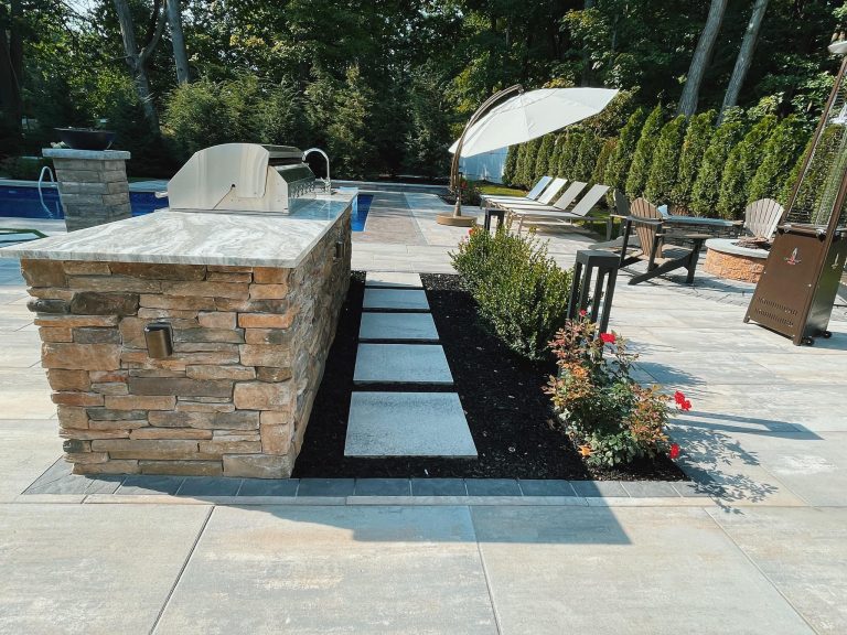 A modern paver patio in Clifton Park, NY, with stone accents and lush landscaping.