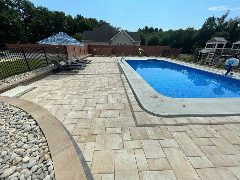 Paver patio with border inlays surrounding a beautiful swimming pool in a backyard in Clifton Park, NY, installed by BlackDiamondDesign Landscaping