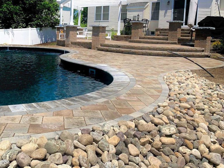 Swimming pool surrounded by a paver patio pool deck, fire pit, multiple steps leading up to the back of the home with additional paver patio space and a pergola in Saratoga Springs, NY