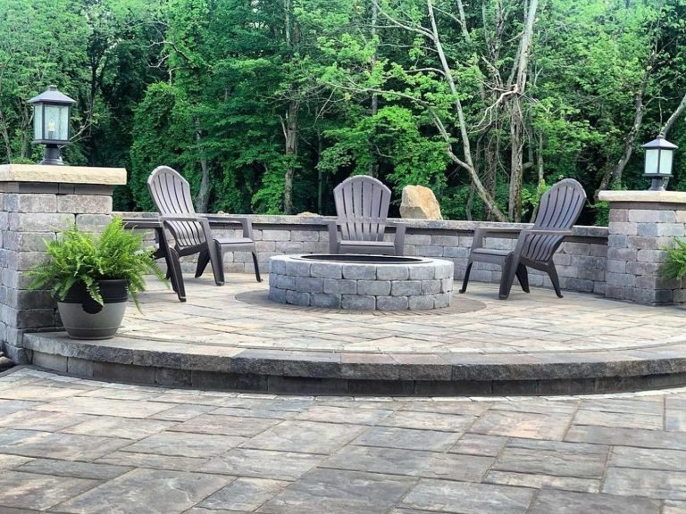 Close-up view of a fire pit sitting wall with two decorative stone pillars and a raised paver patio in a residential backyard in North Greenbush, NY