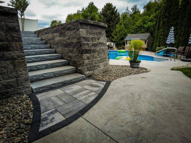 A luxurious backyard patio in Halfmoon, NY, with a seating wall and fire pit.
